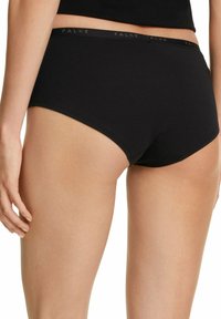 Slip in cotone nero dal tessuto morbido, con vita elastica decorata dal logo "FALKE", presenta una vestibilità a vita media e un design a copertura totale.
