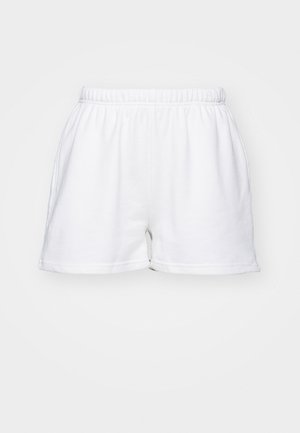 Hvite bomullsshorts med elastisk midje, sidelommer og en avslappet passform mot en ensfarget bakgrunn.