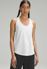 White tank top in a soft, lightweight fabric with a round neckline and a relaxed fit, paired with black pants. Smooth texture, no patterns.