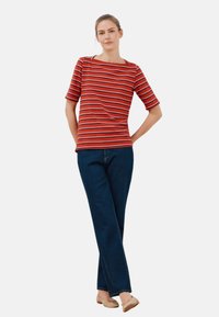 Rød og hvid stribet kortærmet top med vid halsudskæring, parret med mørkeblå lige ben jeans og beige flade sko.