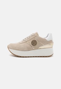 Baskets en suède beige avec un talon blanc, des accents dorés, un logo rond sur le côté et une semelle épaisse en blanc avec un grip texturé.