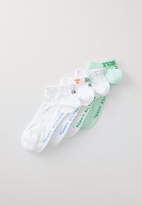 Five pairs of ankle socks in white and mint green, made of cotton, featuring speckled patterns and logo text in varying colors.