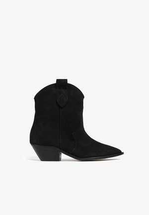 Black suede cowboy boots with a pointed toe, curved stitching detail, and a low stacked heel. Features a pull tab at the back.