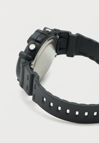 Μαύρο ψηφιακό ρολόι χειρός με λουρί από καουτσούκ, μεταλλικό πίσω κάλυμμα και πλευρικά κουμπιά, απεικονιζόμενο σε λευκό φόντο.