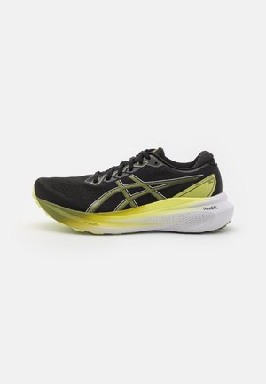 Baskets de course noires avec accents réfléchissants, semelle intermédiaire jaune, tige texturée et semelle blanche rembourrée. Dotées de lacets et du logo de la marque.