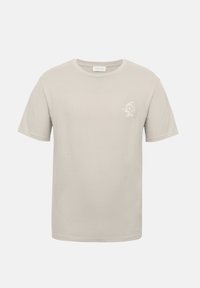 Απλό ανοιχτό μπεζ κοντομάνικο T-shirt με στρογγυλή λαιμόκοψη και μικρό λευκό γραφικό δράκου στην αριστερή πλευρά του στήθους.