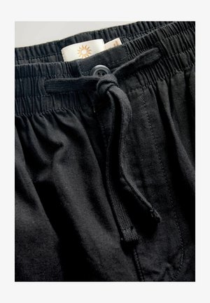 Zwarte shorts met elastische tailleband en een trekkoord. Heeft een gladde textuur en plooit bij de taille. Label zichtbaar aan de binnenkant.