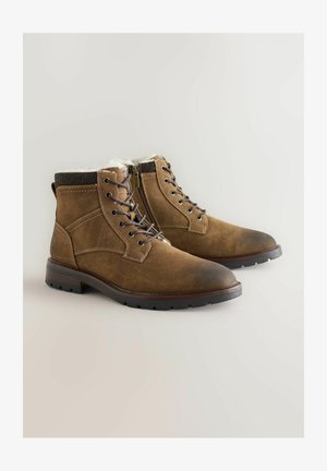 Hnědé semišové kotníkové boty s texturovaným tmavým límcem, vybavené zipem a klasickými šněrováním, a pevnou gumovou podrážkou.