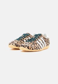Αθλητικά παπούτσια με λεοπάρ σχέδιο, τρεις λευκές ρίγες, πράσινα κορδόνια και υφή στην επιφάνεια. Σόλα από καουτσούκ και επένδυση για άνεση.