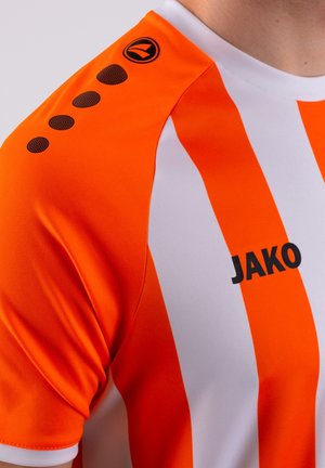 Oranje en witte gestreepte jersey met zwart logo "JAKO" en zes ronde accenten op de schouder. Gladde stoftextuur, korte mouwen.