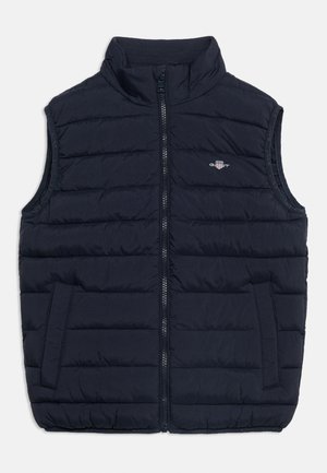 Marineblauw doorgestikt mouwloos vest met een ritssluiting aan de voorkant, twee zijzakken en een klein geborduurd logo op de borst.