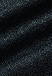 Zbliżenie na ciemnoniebieską teksturowaną tkaninę z ciasno tkanym wzorem i subtelnymi refleksami na złożonych sekcjach.