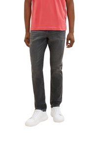 Graue Jeans aus Denim mit geradem Schnitt, mittlerem Waschgang, dezentem Ausbleichen und Fünf-Taschen-Design, kombiniert mit weißen Sneakers und einem korallenfarbenen Hemd.