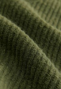 Olijfgroen stof met een ribbelige, gestructureerde oppervlakte. Het materiaal lijkt zacht en pluizig, met variërende groentinten.