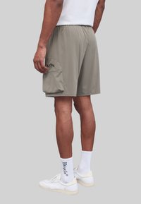 Lichtgrijze, knielange shorts van een soepele, lichte stof. Voorzien van een elastische tailleband en een zijvak met klep.