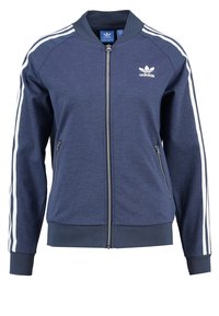 Námořnická modrá bomber bunda Adidas s bílými pruhy na rukávech, zipem, bočními kapsami a logem na hrudi. Měkká textilie.