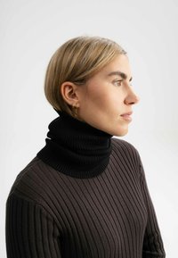 Zwarte geribde coltrui met een hoge, opgevouwen kraag, voorzien van een textuurpatroon en een aansluitend ontwerp.