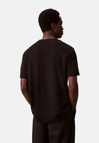 Zwarte katoenen t-shirt met korte mouwen, ronde hals en een ontspannen pasvorm. De stof heeft een zachte textuur en een eenvoudig, effen ontwerp.