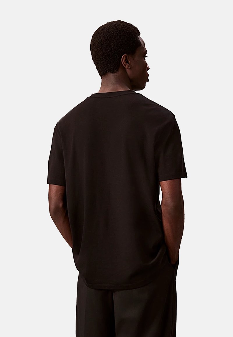 Zwarte katoenen t-shirt met korte mouwen, ronde hals en een ontspannen pasvorm. De stof heeft een zachte textuur en een eenvoudig, effen ontwerp.