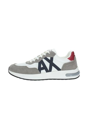 Zapatilla blanca con detalles en ante gris, logo "AX" negro en el lateral, parche rojo en el talón y suela blanca con piso negro.