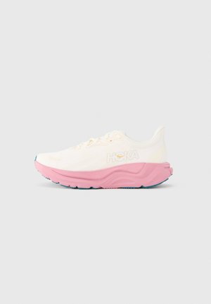 Lightweight running shoe in cream with a pink midsole and teal outsole. Features a textured upper and logo detail on the side.