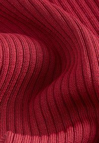 Tejido de textura acanalada roja, con líneas verticales. El material parece suave, con un ligero brillo y un intrincado patrón de punto en toda su superficie.