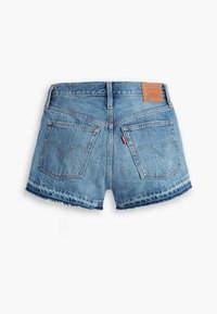 Short en denim bleu avec ourlets effilochés, deux poches arrière et un patch en cuir marron de la marque sur la ceinture.