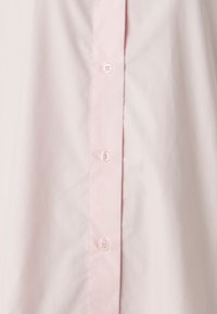Light pink button-up shirt with a smooth texture. Six buttons along the placket, classic collar, and slightly structured fabric.