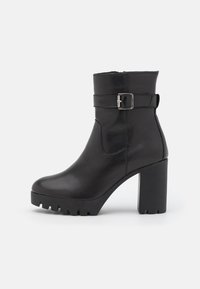 Černá kožená kotníková botka s robustním vysokým podpatkem, se sponou na boku a texturovanou podrážkou pro lepší přilnavost. Hladký povrch a elegantní design.