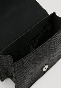 Borsa nera con trama a rettile, dotata di chiusura a calamita e fodera in tessuto. Tasche interne per l'organizzazione.