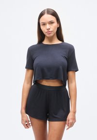 Μαύρο ριμπ τοπ cropped με κοντά μανίκια και ταιριαστά σορτς με ψηλή μέση. Μαλακή υφή, άνετη εφαρμογή και μινιμαλιστικός σχεδιασμός.
