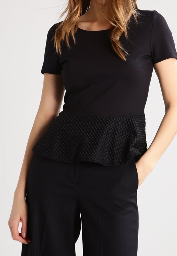 Černý top s krátkým rukávem, který má texturovaný peplum lem s vzorovaným, mírně volánkovým designem, spárovaný s černými kalhotami s širokými nohavicemi.
