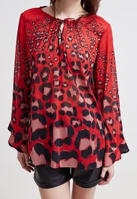Blusa rossa a maniche lunghe in tessuto leggero con stampa animale nera e rosa, con scollo arricciato e maniche fluide.
