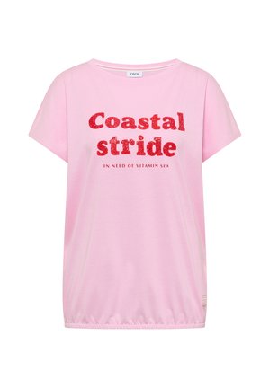 Chemise rose clair à manches courtes avec texte pailleté rouge « Coastal stride » et texte plus petit « In need of vitamin sea » sur le devant, ourlet élastique en bas.