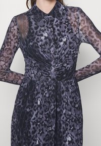 Langärmiges Kleid aus transparentem schwarz-grauen Leopardenmuster, mit kragenähnlichem Hals, gerafftem Bund und weich fließendem Stoff.