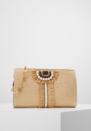 Pochette rectangulaire beige tissée avec un volant décoratif, des perles marron et blanches, une rangée de perles et une chaîne dorée sur un socle blanc.