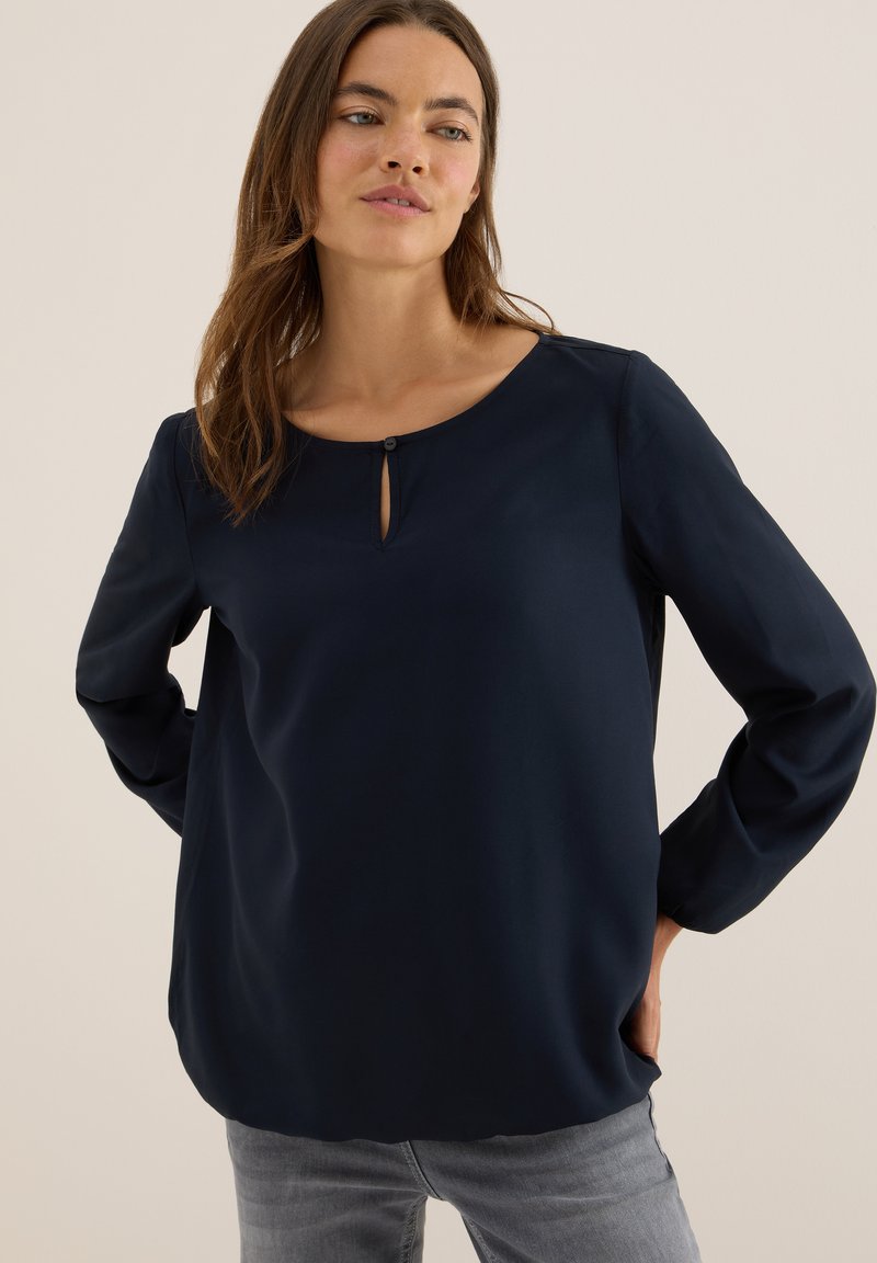 Blusa de manga larga azul marino con escote redondo, que presenta un pequeño detalle de ojal en la parte delantera y una textura suave y elegante.