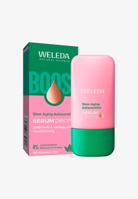 Butelka i pudełko kropli serum Weleda Slow Aging Astaxanthin z zielonym i różowym wzorem, podkreślające antyoksydacyjne ekstrakty roślinne.