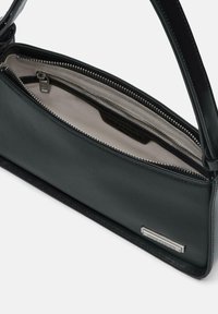 Borsa a mano in pelle nera con una texture liscia, chiusura con zip e interno foderato. Presenta una placca con logo in tono argento e un design strutturato.