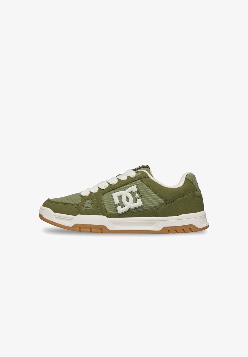Χαμηλό sneaker ελιάς με λευκά κορδόνια, επενδεδυμένο γιακά, λογότυπο DC στην πλευρά και λευκή σόλα με ταμπά πέλμα.
