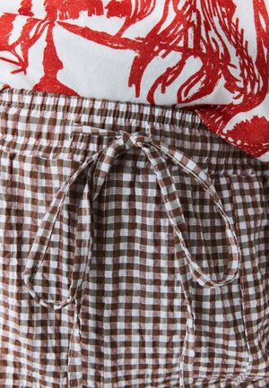 Rudos ir baltos spalvų languotas audinys su elastine liemeniu ir surišama raišteliu. Raudonas gėlių rašto viršus matomas dalinai virš juosmens juostos.