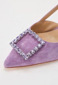 Chaussure en daim violet avec un bout pointu, présentant une boucle carrée décorative ornée de strass violets clairs.
