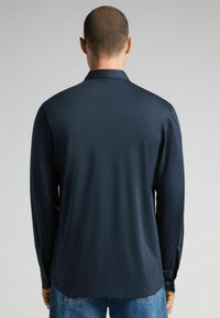 Marineblauw overhemd met lange mouwen, voorzien van een kraag, een zachte textuur en knopenmanchetten, gecombineerd met lichtblauwe denim jeans.