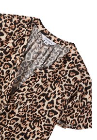 Blusa con stampa leopardata, caratterizzata da scollo a V, maniche corte, texture seta e una palette di colori nera e beige. Etichetta visibile sul collo.