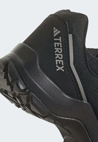 Czarne buty trekkingowe z teksturowaną siateczkową cholewką, gumową podeszwą z agresywnym wzorem bieżnika oraz wyraźnym logo "TERREX".