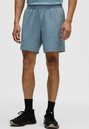 Vaalean siniset urheilushortsit, joissa on nyörivyö, sivutaskut ja sileä pinta, yhdistetty mustiin tennareihin ja sukkiin.