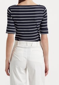 Marinblå och vit randig t-shirt med korta ärmar, bred ringning, matchad med vita högmidjade byxor med bakfickor.