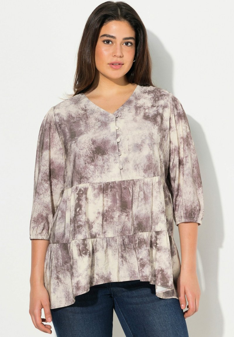 Blusa a maniche lunghe con scollo a V in tessuto morbido e leggero. Presenta un motivo tie-dye in crema e grigio, con dettagli di bottoni e un design a più strati.