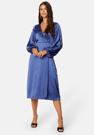 Satijnen wikkeljurk in diepblauw met lange opgezette mouwen, v-hals en een vloeiende midi-lengte rok. Heeft een strik taille en een soepele textuur.