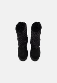 Černé kozačky po lýtka s huňatými, texturovanými koženými manžetami a hladkou nubukovou částí chodidla, zobrazené z hory na bílém pozadí.